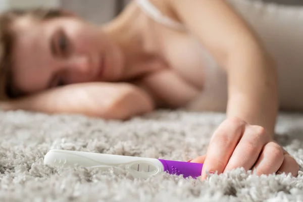 Elinde hamilelik testi olan genç bir kadın.