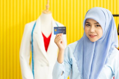 Terzisinde ya da atölyesinde dikiş makinesi kullanarak genç ve güzel Müslüman moda tasarımcısının ellerini kapat. Pembe elbiseler..