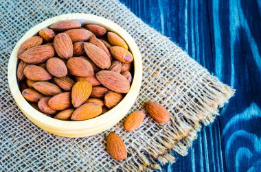 Badem kenevir arka plan üzerinde kahverengi ahşap kase masaya koyun