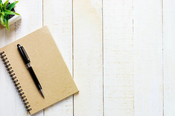 Beyaz masa üzerinde kahverengi not defteri yer üzerinde siyah kalem