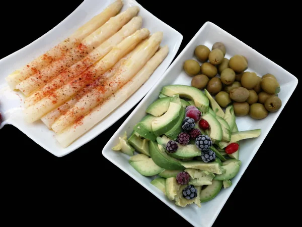 trays with seasoned asparagus, avocados and olives