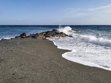 Bir sonbahar öğleden sonrasında dalgalar ve kayalarla dramatik bir deniz.