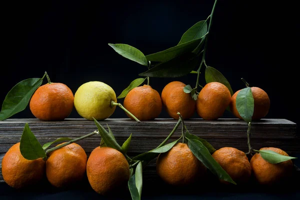 Siyah arkaplanda yaprakları olan organik mandalinalar