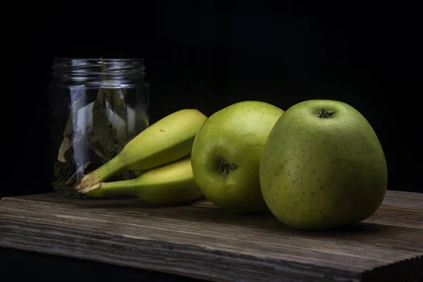 bananas and green apples on black background
