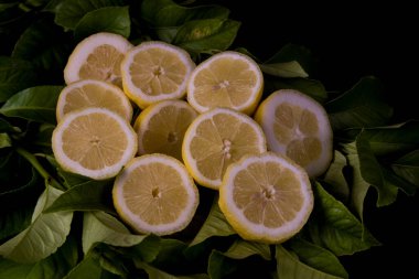 Limon yapraklarıyla ikiye bölünmüş taze limonlar.