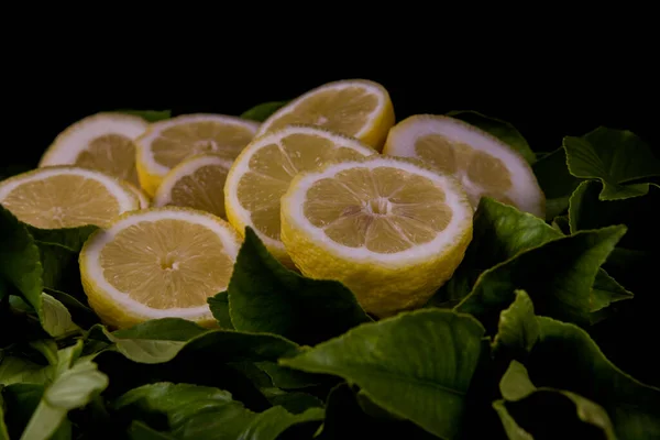 fresh lemons cut in half on lemon leaves