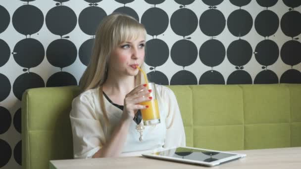 Modelo atractivo bebiendo jugo de naranja en la cafetería — Vídeos de Stock