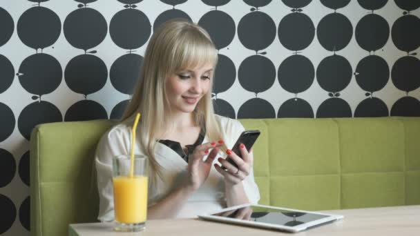 Chica joven bebiendo jugo de naranja en el café — Vídeo de stock