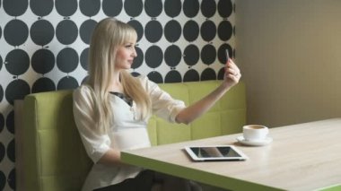 Sarışın kız selfie bir gri cep telefonu kullanarak yapar