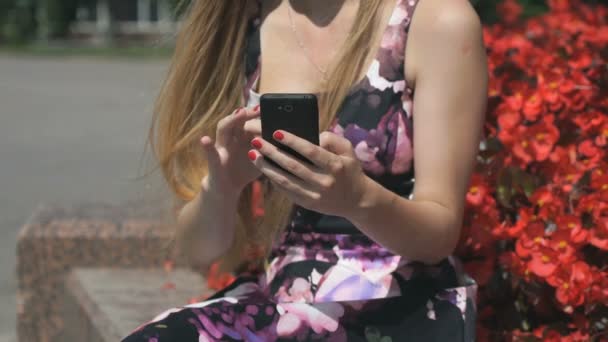 Молодая девушка держит мобильный телефон и читает сообщения — стоковое видео