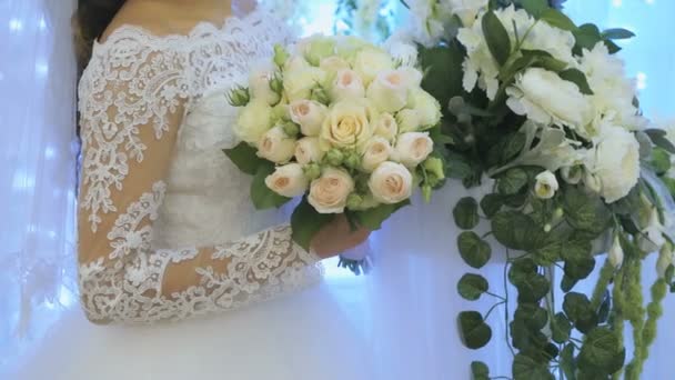 La novia de pie junto al arco de flores en el interior — Vídeo de stock