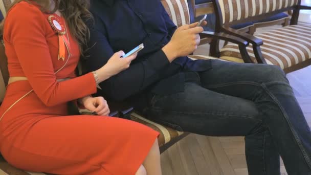 Девушка и мужчина просматривают фотографии с помощью своих мобильных телефонов — стоковое видео