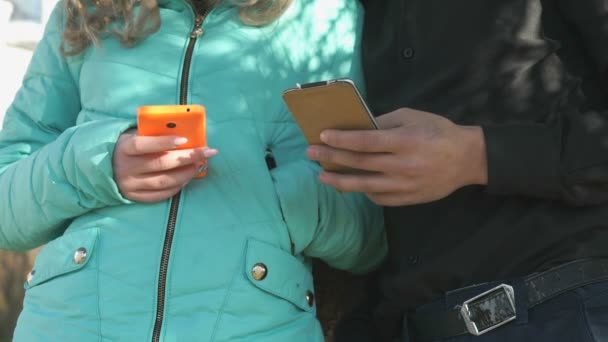 Mädchen und Junge stehen und halten die Smartphones — Stockvideo