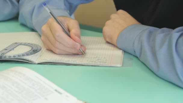 Der Junge schreibt Text in ein Notizbuch drinnen — Stockvideo