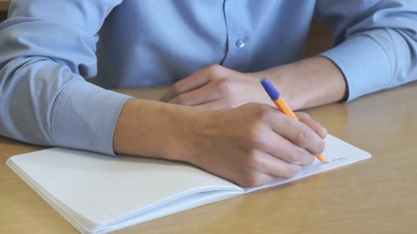 Étudiant écrit du texte dans un cahier à l'intérieur — Video