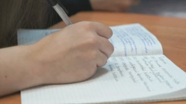 Kız öğrenci ders içinde defterini yazıyor