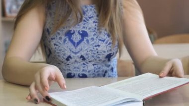 Masada oturan kız öğrenci ders kitabı okur
