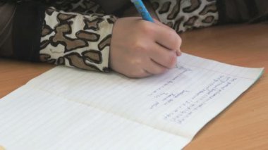 Kız bir defterini bir kalem kullanarak metni yazar