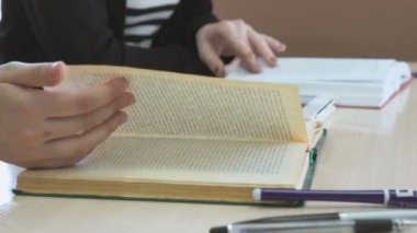 Kız öğrenci ders kitabı sayfa ders sırasında çevirir.