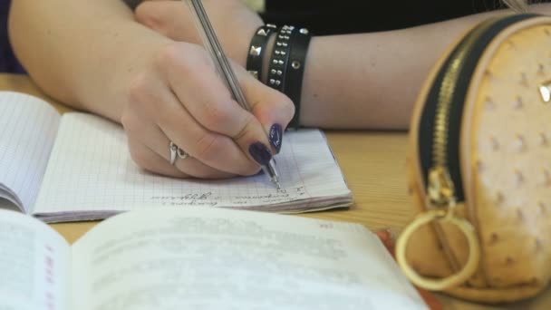 Estudiante escribe texto en un libro de ejercicios usando una pluma — Vídeos de Stock