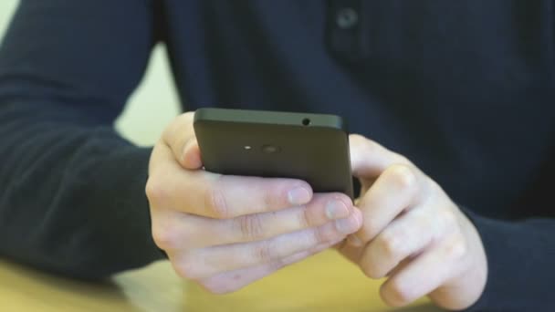 Student som sitter vid skrivbordet håller smartphone — Stockvideo