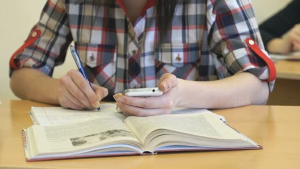 Dívka sedí u stolu zapisuje text v copybook — Stock video