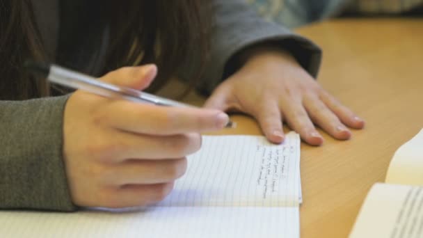 Écolière assise au bureau de l'école tient un stylo — Video