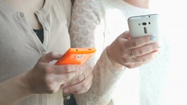İki kız akıllı telefonlar kullanarak fotoğrafları izlerken
