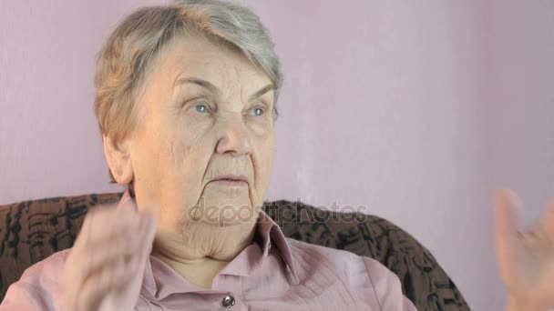 Mujer de 80 años sentada en el interior cubre las manos de la cara — Vídeos de Stock