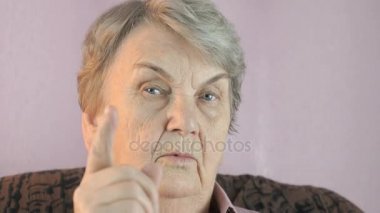 Yaşlı kadın onun parmağı yüz önünde dalgalar