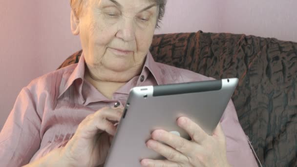 Elderly woman holding the silver tablet computer — Stock Video