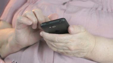 Yaşlı bir kadın metni siyah Smartphone'da türleri.