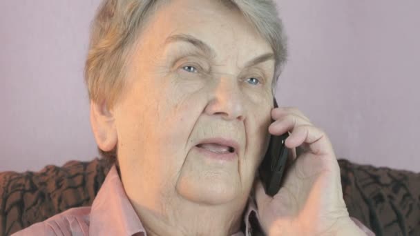 Bejaarde vrouw gesprekken over smartphone met glimlach — Stockvideo