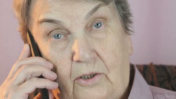Пожилая женщина разговаривает на смартфоне с улыбкой — стоковое видео
