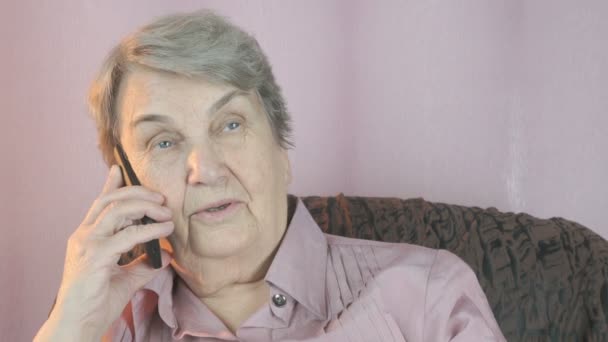 Mujer vieja sonriendo habla en el teléfono móvil. De cerca. — Vídeos de Stock