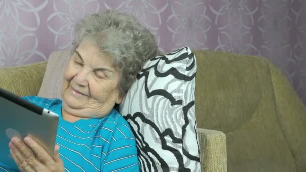 Ηλικιωμένη γυναίκα χαλαρώνει χρησιμοποιώντας έναν υπολογιστή tablet — Αρχείο Βίντεο
