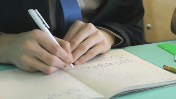 El chico escribe texto en un cuaderno en el interior — Vídeos de Stock