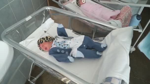 Медсестра одевает новорожденного в больничную палату — стоковое видео