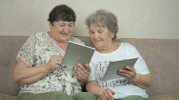 Twee oude vrouwen houden van de zilveren digitale tabletten — Stockvideo