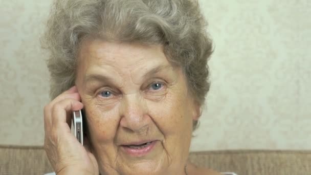 A velha falando em um telefone celular em casa — Vídeo de Stock