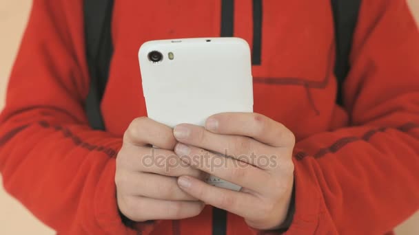 L'adolescent tenant un téléphone portable blanc à l'intérieur — Video