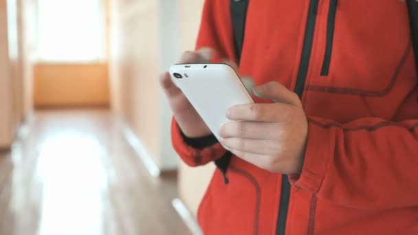 Ο έφηβος που κατέχουν ένα λευκό κινητό τηλέφωνο σε εσωτερικούς χώρους — Αρχείο Βίντεο