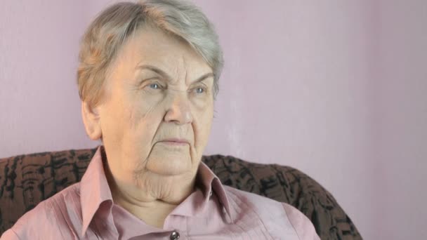 Velha mulher sentada dentro de casa cobre rosto suas mãos — Vídeo de Stock