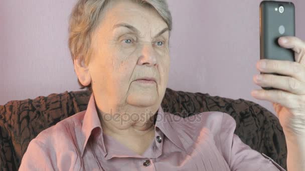 Elderly woman holding the smartphone indoors — Stock Video