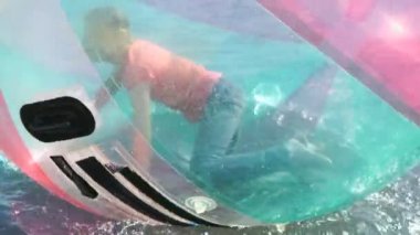 Su yüzeyindeki büyük şişme top içinde çocuk