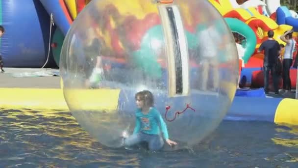 Niña platillos dentro de bola inflable grande — Vídeo de stock