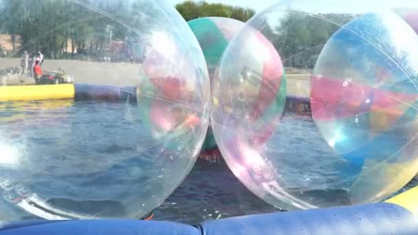 Dziecko wewnątrz duże nadmuchiwane piłki na powierzchni wody — Wideo stockowe