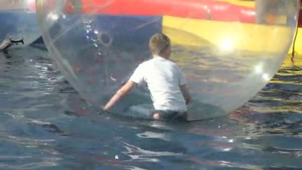 물에서 큰 팽창 식 공 안쪽 작은 소년 — 비디오