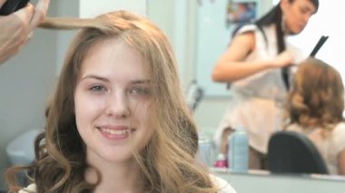 Stilist bukleler kahverengi saçlı bir kıvırma kullanarak yapar