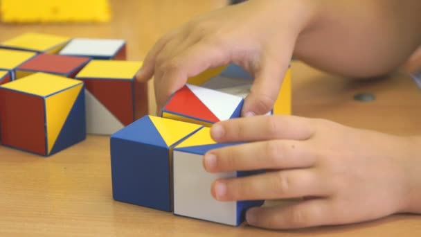 Menino pré-escolar coleta figura usando cubos coloridos — Vídeo de Stock